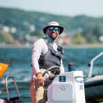 A man in a hat and sunglasses on a boat.