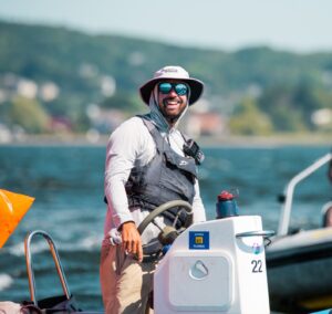 A man in a hat and sunglasses on a boat.